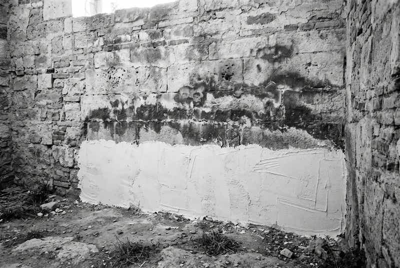 Sockel einer alten Mauer mit frischem Sanierputz