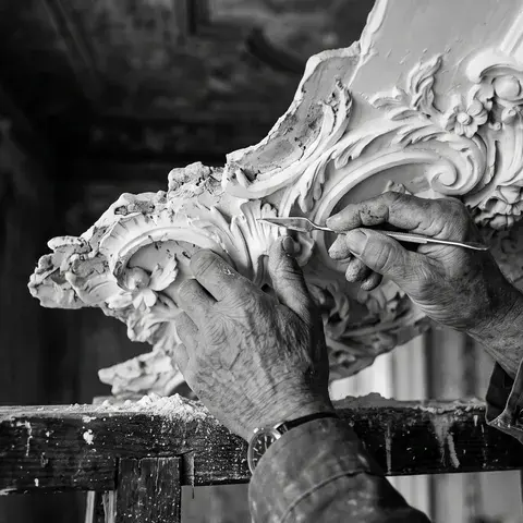 Hände eines Restaurators bei der Arbeit an einem historischen Stuckornament