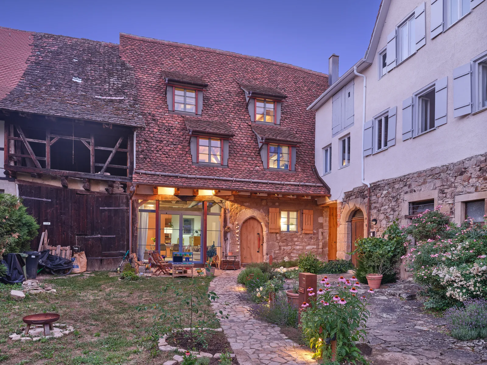 Innenhof der Klosterscheune mit Fachwerk, Sandsteinmauern und beleuchteten Fenstern