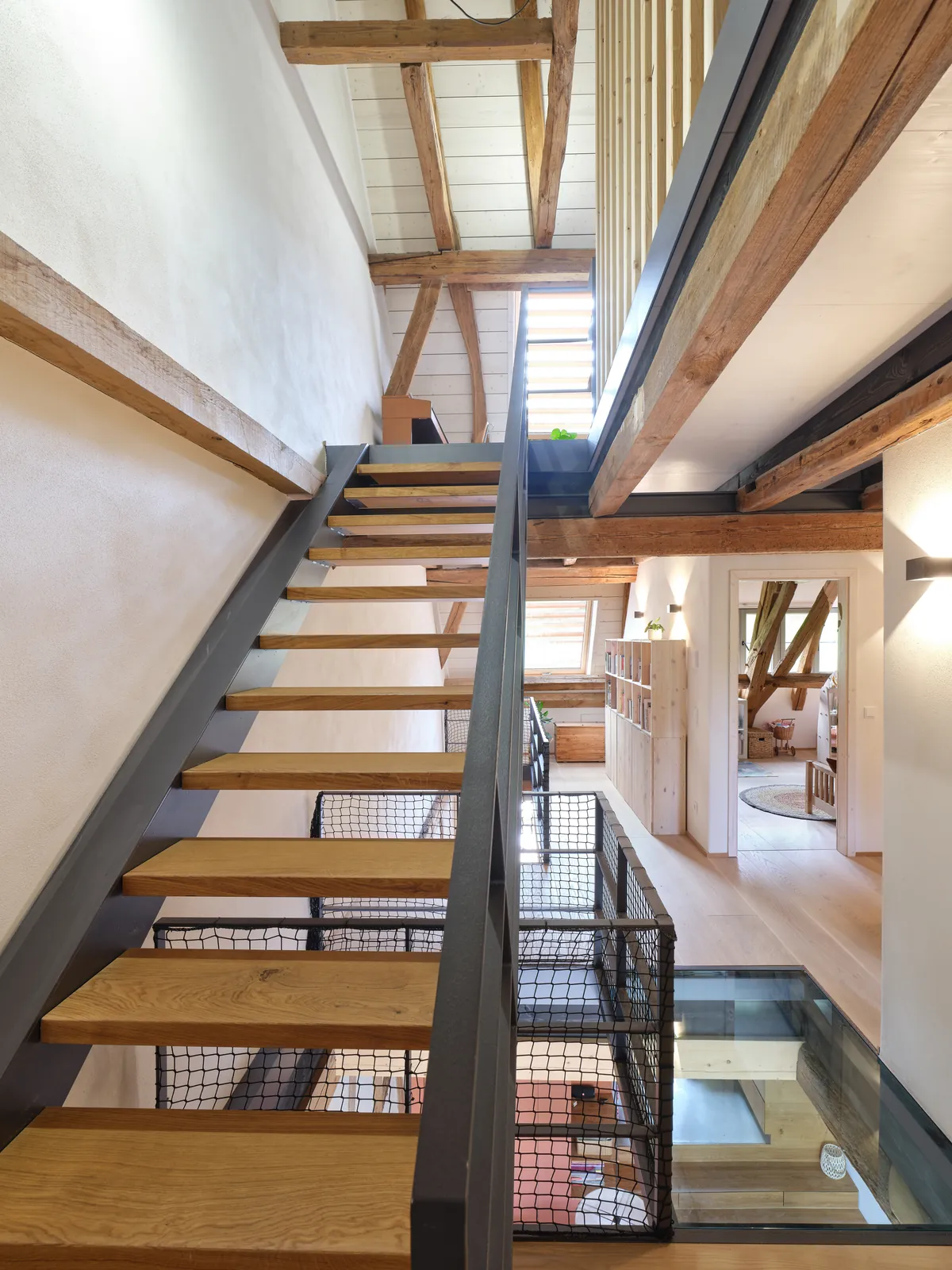 Stahltreppe mit Holzstufen zwischen alten Balken